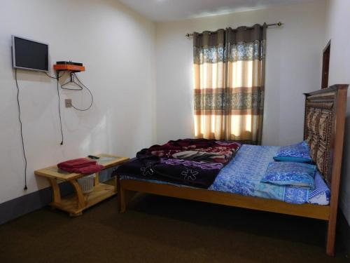 um pequeno quarto com uma cama e uma televisão em Mountain View Hotel em Bālākot