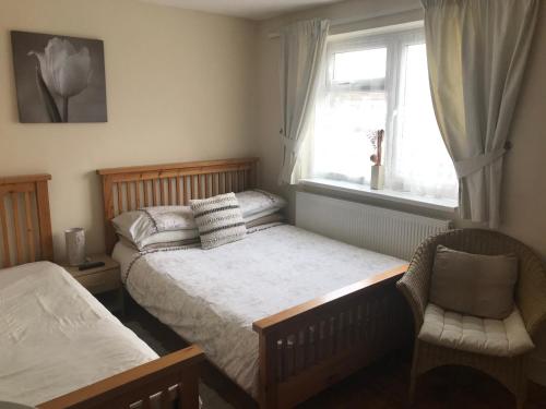 a bedroom with two beds and a chair and a window at Abbey Lodge Guest House in Southampton