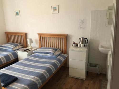two twin beds in a small room with a sink at Abbey Lodge Guest House in Southampton