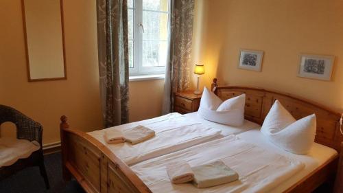 una camera da letto con un letto con lenzuola e cuscini bianchi di Pension Am Holzgraben a Lübbenau