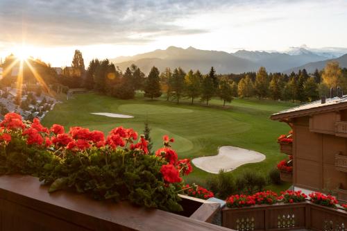 a view of a golf course from a balcony with flowers at Guarda Golf Hotel & Residences in Crans-Montana