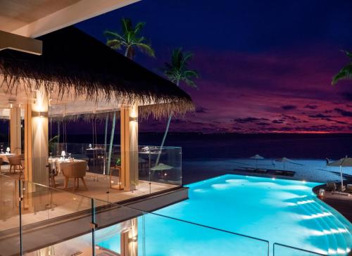 a swimming pool with a view of the ocean at night at Baglioni Resort Maldives - Luxury All Inclusive in Dhaalu Atoll