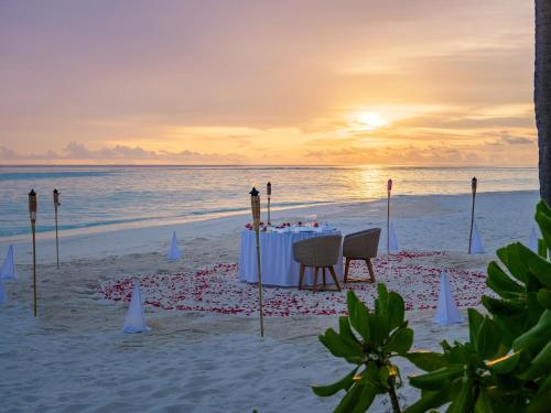 a dinner table on the beach at sunset at Baglioni Resort Maldives - Luxury All Inclusive in Dhaalu Atoll