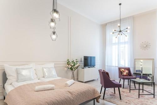 a white bedroom with a large bed and chairs at Milano Design Apartment City Center in Budapest