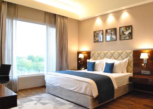 a bedroom with a large bed and a large window at Ramada by Wyndham Gandhidham Shinay in Gandhidham