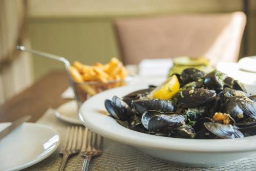 a bowl of mussels on a table with a plate of fries at Red Lion Hotel in Clovelly