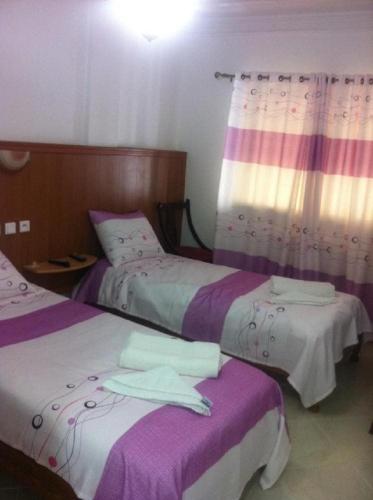 a bedroom with two beds with purple and white sheets at OUMAYA SAFA in Alger