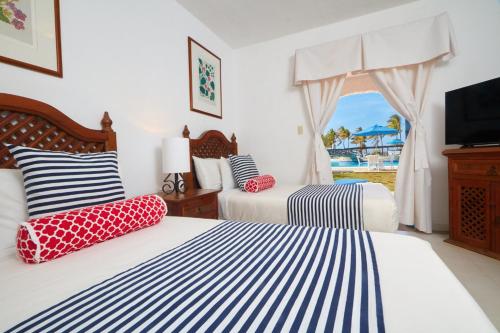 a bedroom with two beds and a window with a view at Costa Caribe Hotel Beach & Resort in La Galera