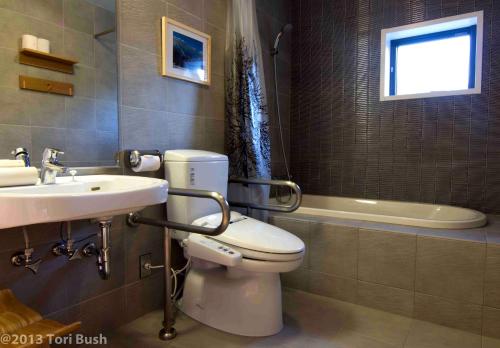 a bathroom with a toilet and a sink and a tub at Koharu Resort Hotel & Suites in Hakuba