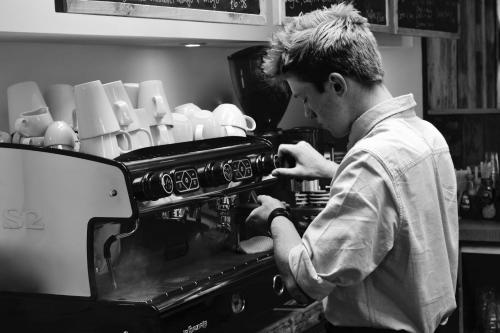 a man standing in a kitchen looking at a coffeemachine at Banbury Hill Farm Bed & Breakfast in Charlbury