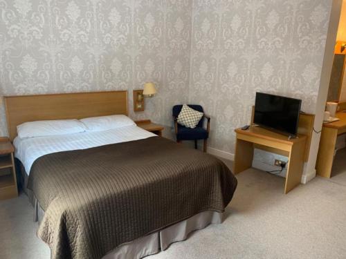 a bedroom with a bed and a desk with a television at Waterford Lodge Hotel in Morpeth