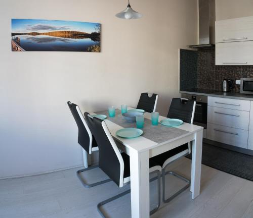 a white dining room table with black chairs and a kitchen at Apartment Třída Míru in Pardubice