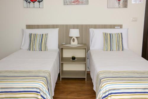 ein Schlafzimmer mit 2 Betten und einem Nachttisch mit einer Lampe in der Unterkunft B&B Incanto Salento in Ugento