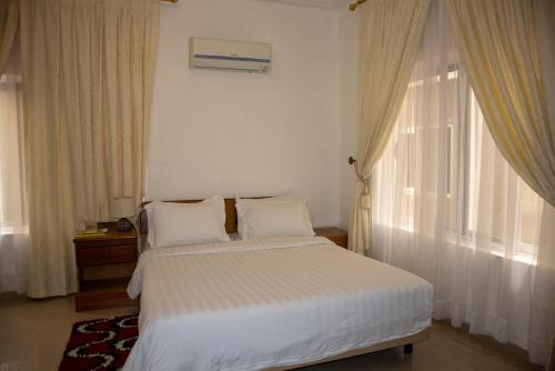 a bedroom with a bed with white sheets and a window at His Majesty's Hotel and Apartments in Accra