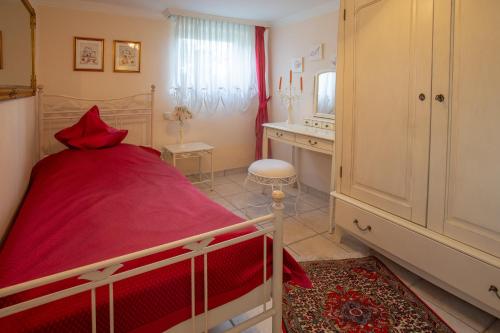 a bedroom with a red bed and a dressing table at Haus Kottenborn am Nürburgring in Kottenborn