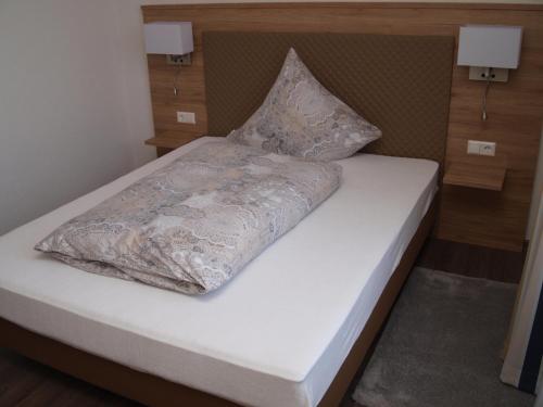 a white bed with a pillow on top of it at Hotel Anker garni in Rastatt