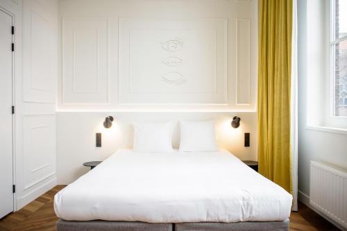 a bedroom with a white bed and yellow curtains at Hotel Mariënhage in Eindhoven