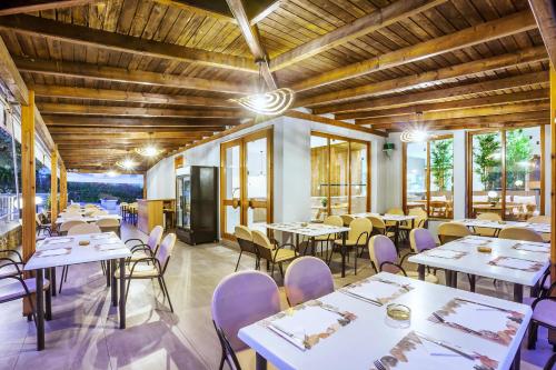 un restaurant avec des tables blanches, des chaises et des fenêtres dans l'établissement Palladium Hotel, à Kriopigi