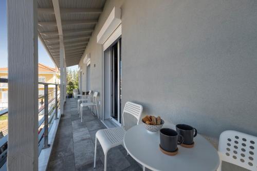 a balcony with a white table and chairs on a building at Macrame Suites in Tríkala
