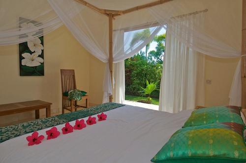 a bedroom with a bed with red flowers on it at Villa Mawar in Pengastulan