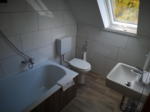 ein Bad mit einer Badewanne, einem WC und einem Fenster in der Unterkunft Wolfs Gasthaus in Braunschweig