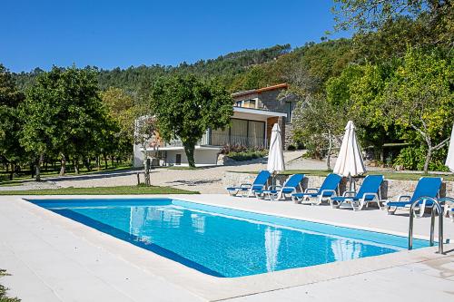 a swimming pool with lounge chairs and umbrellas at Regada House in Vieira do Minho