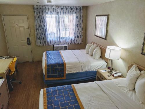 a hotel room with two beds and a window at Days Inn by Wyndham Bullhead City in Bullhead City
