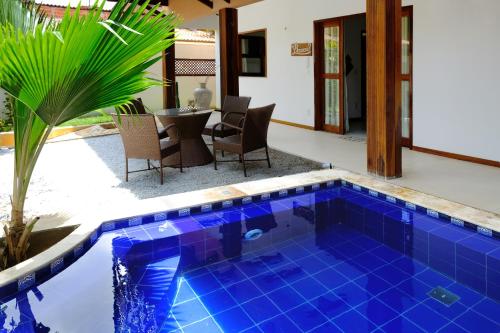 a pool with blue tile in a backyard with a table at Hotel e Pousada La Dolce Vita in Canoa Quebrada