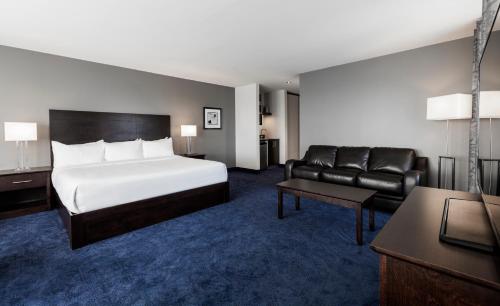 a hotel room with a bed and a couch at Imperia Hotel & Suites Saint-Eustache in Saint-Eustache