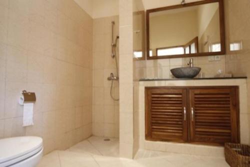 Un baño con lavabo, inodoro y espejo. en Villa Mawar, en Pengastulan