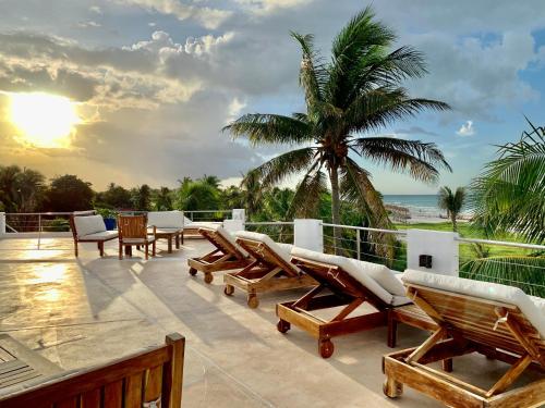 a balcony with lounge chairs and a palm tree at Hotel La Casa Cielo solo adultos in El Cuyo
