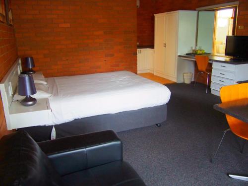 a bedroom with a bed and a brick wall at Essendon Motel in Melbourne