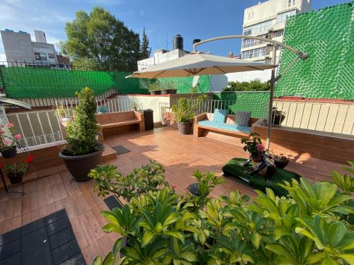 a patio with an umbrella and benches and plants at Roma Sur 222 in Mexico City