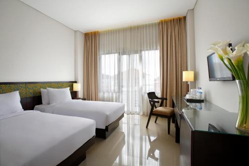 a hotel room with two beds and a window at Hotel Surya Yudha Purwokerto in Purwokerto