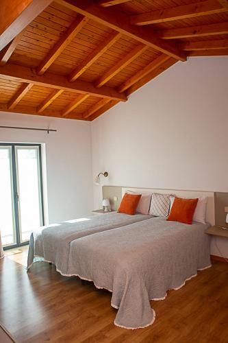 a large bed in a white room with wooden ceilings at Regada House in Vieira do Minho