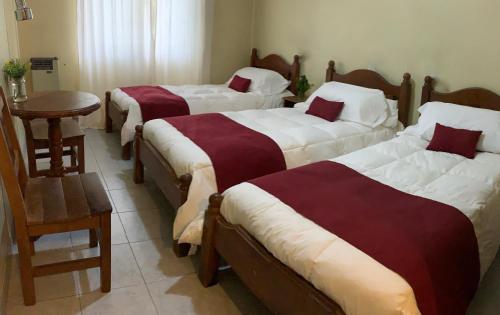 three beds in a room with a table and chairs at Hotel Olijnyk in Rosario del Tala