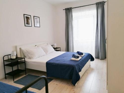 a bedroom with a bed with a blue blanket and a window at Apartments Valiža in Senj
