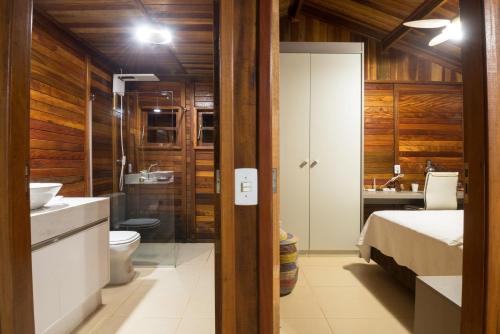 a bathroom with a bed a sink and a toilet at Casinha de Madeira no Vale do Capão in Vale do Capao