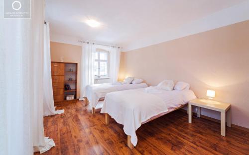 two beds in a white room with wooden floors at Apartament Pod 13 in Kowary