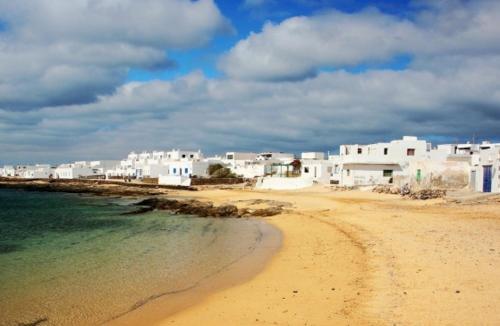 una playa con un grupo de edificios blancos y el océano en Apartamento las Crucetas, en Caleta de Sebo