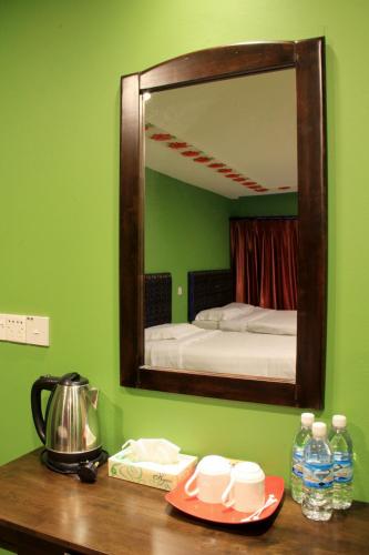 a mirror on a green wall above a wooden table at White Cottage in Kuching