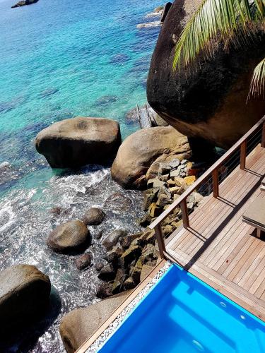 a swimming pool next to the ocean with rocks at Marquise & Infinity villas in Glacis