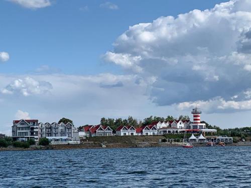 a group of houses and a lighthouse on a body of water at Der LeuchtTurm-Gastro GmbH in Geierswalde