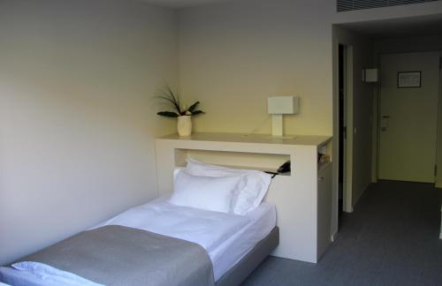 a bedroom with a bed and a table with a plant on it at Hotel Lavaux in Cully