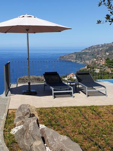 - deux chaises et un parasol à côté de la piscine dans l'établissement Casa Atlantico tropischer Seitenflügel, à Ribeira Brava