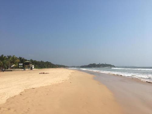 une plage de sable avec l'océan en arrière-plan dans l'établissement villa layanga - riverside guestrooms, à Aluthgama