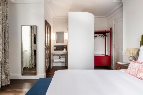 a bedroom with a white bed and a mirror at La Maison d'Estournel in Saint-Estèphe