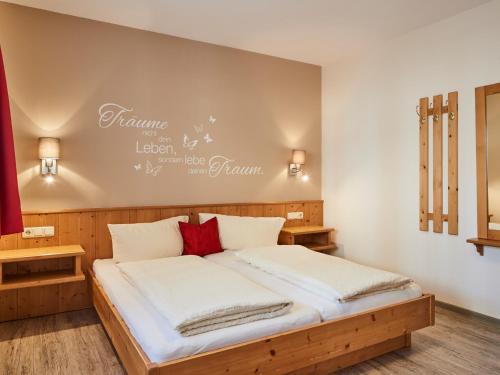 um quarto com uma cama com lençóis brancos e almofadas vermelhas em Haus Lenz em Serfaus