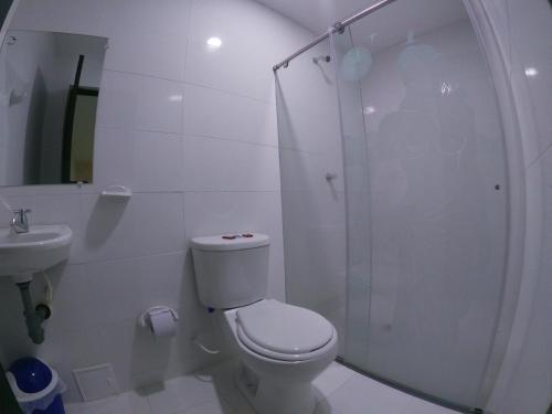 a white bathroom with a toilet and a shower at Hotel Kasvel in Valledupar