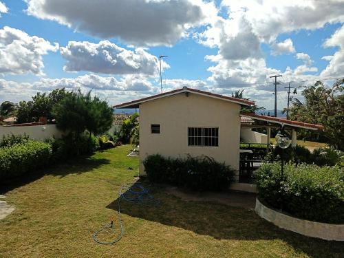 a small white house with a hose in the yard at Pousada Vale Encantado in Serra de São Bento